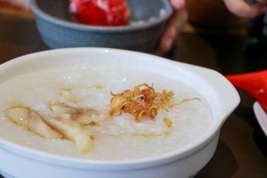 Dilimlenmiş kereviz yaprağı, kızarmış hamur köftesi ve kızarmış arpacık soğanı gibi beyaz bir tabakta servis edilen yulaf lapası malzemelerinin yakın çekim fotoğrafını çek.