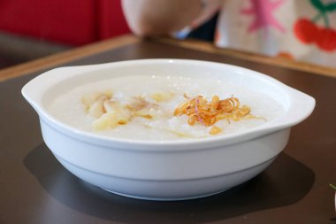 Dilimlenmiş kereviz yaprağı, kızarmış hamur köftesi ve kızarmış arpacık soğanı gibi beyaz bir tabakta servis edilen yulaf lapası malzemelerinin yakın çekim fotoğrafını çek.