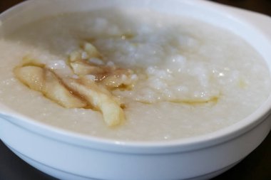 Dilimlenmiş kereviz yaprağı, kızarmış hamur köftesi ve kızarmış arpacık soğanı gibi beyaz bir tabakta servis edilen yulaf lapası malzemelerinin yakın çekim fotoğrafını çek.