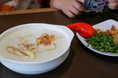 Dilimlenmiş kereviz yaprağı, kızarmış hamur köftesi ve kızarmış arpacık soğanı gibi beyaz bir tabakta servis edilen yulaf lapası malzemelerinin yakın çekim fotoğrafını çek.