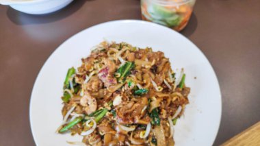 Otantik bir Güneydoğu Asya sokak yemeği olan Char Kway Teow 'a yakın. Yanında fasulye filizi, yumurta tavuklu karides..