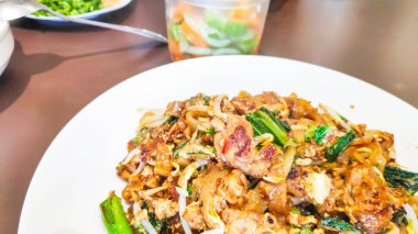 Otantik bir Güneydoğu Asya sokak yemeği olan Char Kway Teow 'a yakın. Yanında fasulye filizi, yumurta tavuklu karides..