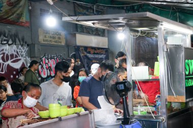 Müşteriler, Endonezya 'nın Bandung kentindeki işlek bir açık hava tezgahında lezzetli Endonezya sokak yemekleri için sırada bekliyorlar..