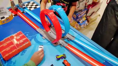 Oyuncak arabaları fırlatırken çocukların elleri ve yüzleri heyecanlanıyor.