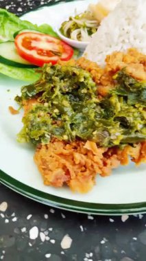 Kızarmış tavuk ya da baharatlı yeşil biber soslu ayam geprek, pilav ve krakerle servis edilir..