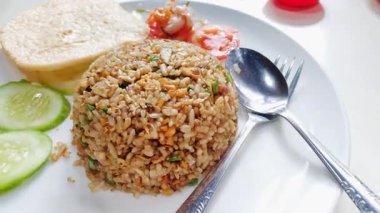 Taze kesilmiş salatalık ve domatesle servis edilen bir tabak otantik Endonezya usulü kızarmış pirinç.