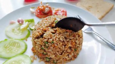 Taze kesilmiş salatalık ve domatesle servis edilen bir tabak otantik Endonezya usulü kızarmış pirinç.