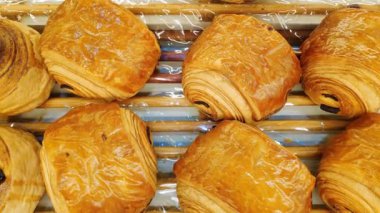 Kafedeki ahşap bir vitrinde çeşitli taze kruvasanlardan oluşan düzenli bir düzenleme..