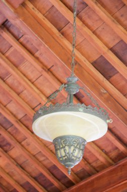 Süslü metal bir kafesi ve ahşap tavanda buzlu cam kasesi olan antika bir kolye.