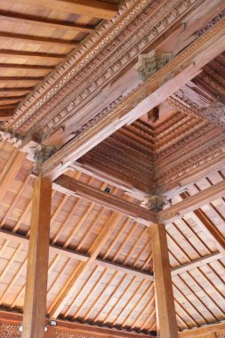 Traditional Indonesian Joglo house ceiling with intricate hand carved wooden details and layered beams