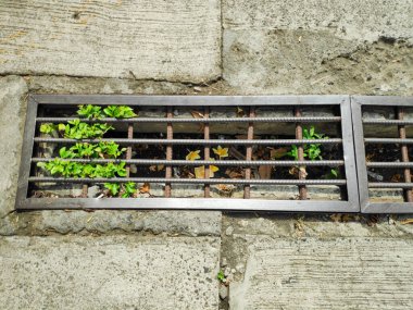 Industrial background featuring a thick cast iron grill designed for heavy traffic and water flow.