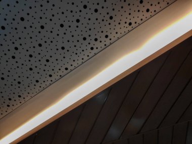 Beyaz delikli akustik paneller ve koyu kahverengi tahta levhalardan oluşan modern iç duvar.