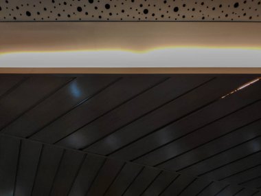 Beyaz delikli akustik paneller ve koyu kahverengi tahta levhalardan oluşan modern iç duvar.