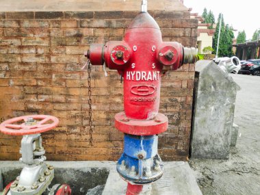 Kırmızı bir açık hava yangın musluğu geleneksel bir Bali kırmızı tuğla duvarına karşı duruyor Denpasar 7 Mayıs 2025