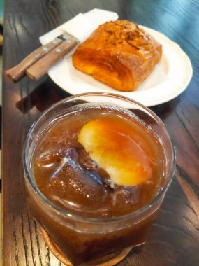 Tazeleyici buzlu limonlu kahveyi, ahşap bir masada şeffaf bir bardakta dilimlenmiş limon dilimiyle kapat.