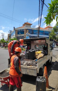 Kuta Bali Endonezya 'daki bir yolda yeni asfaltı düzleştirmek için plaka sıkıştırıcı kullanan inşaat işçisi, 11 Ekim 2025