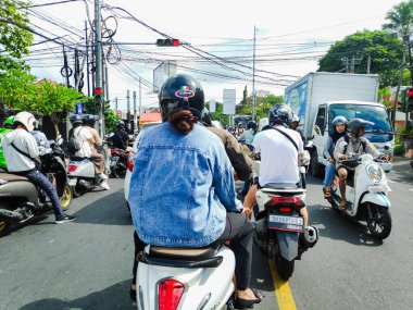 Motorcyclists stopping behind the line at a red light in a busy intersection in Bali Indonesia, Indonesia 5 August 2025