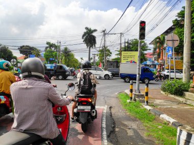 Motorcyclists stopping behind the line at a red light in a busy intersection in Bali Indonesia, Indonesia 5 August 2025