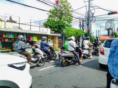 Motorcyclists stopping behind the line at a red light in a busy intersection in Bali Indonesia, Indonesia 5 August 2025