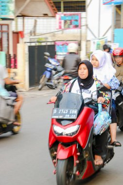 20 Ağustos 2025 'te Bandung, Endonezya' da bir ara sokakta kaskı takmayan bir motosikletçiye tehlikeli sürüş davranışı
