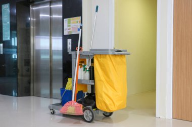 Modern ofis koridorunda temizlik malzemeleri park etmiş profesyonel hademe arabası. Bali, 18 Mart 2025