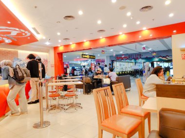 Müşteriler, I Gusti Ngurah Rai Havaalanı Bali, Endonezya 'daki parlak turuncu bir Yoshinoya tezgahından et kasesi sipariş ediyor.