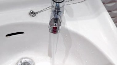 Modern metal bir musluktan akan temiz suyu günlük temizlik ve el yıkama için lavaboya kapatın.