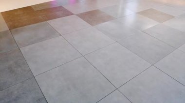 Şehir müşterileri, yansıtıcı fayanslar ve lüks atmosferle çağdaş bir alışveriş merkezi koridorunda yürüyorlar.