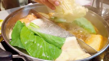 Geleneksel Japon sukiyaki köfteli ve sebzeli yavaş çekim otantik Tayland restoranında sıcak et suyunda kaynıyor.