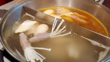 Tuzlu malzemeler ve sosislerle ağır ağır haşlanmış sıcak çorba Japon yemek masasında kaynıyor.