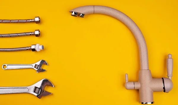 Faucet and flexible hoses on yellow background. Details for installing water tap supply. Adjustable wrench.