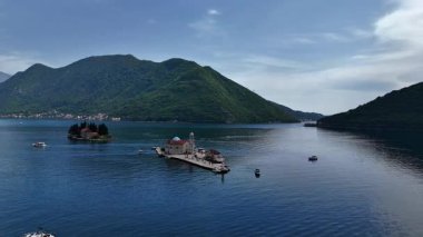 Kotor Körfezi 'ndeki Kayalıklardaki Meryem Kilisesi' nin arka planındaki dağlara karşı. Karadağ 4K stok videosu.