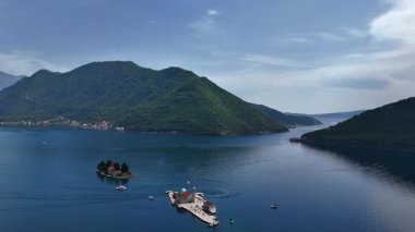 Kotor Körfezi 'ndeki Kayalıklardaki Meryem Kilisesi' nin arka planındaki dağlara karşı. Karadağ 4K stok videosu.