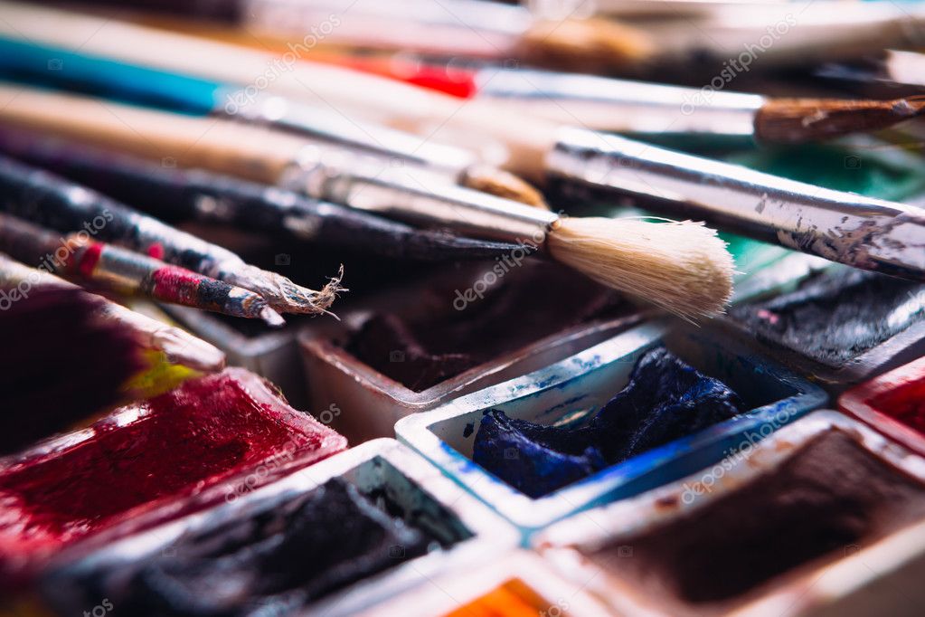 Many brushes and paint for painting on wooden background