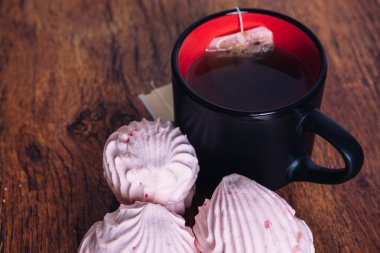 kaç adet pembe hatmi ve ahşap zemin üzerine bir fincan çay