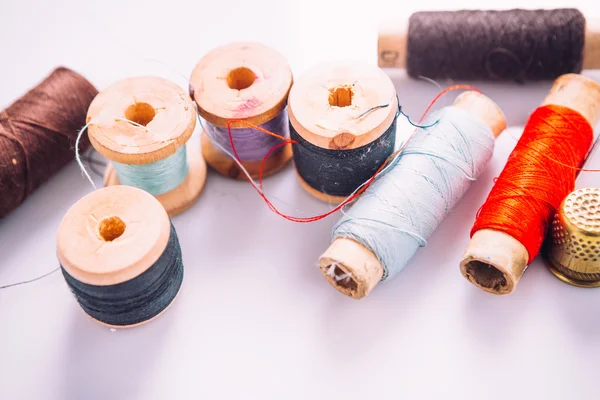 tailor the tool to measure  length, spools of colored thread on a wooden background