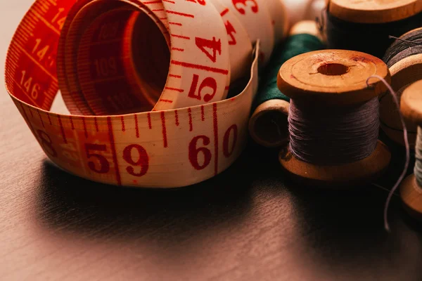 iş parçacığı yüksük ve ahşap arka plan üzerinde ölçüm bandı çok Vintage biriktirir