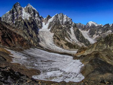 Gürcistan 'ın Kafkasya bölgesindeki Ushba Dağları ve Buzul Dağları engebeli kayalıkları ve açık mavi gökyüzü altındaki karla kaplı görkemli dağlık arazi. Yüksek kalite fotoğraf