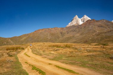 Gürcistan 'da Kuruldi Gölü' nün yakınlarındaki Ushba İkiz Zirvesi: Görkemli Kar Altında Yükselen Tepeler Açık Mavi Gök Altındaki Dağ Çayırı. Yüksek kalite fotoğraf