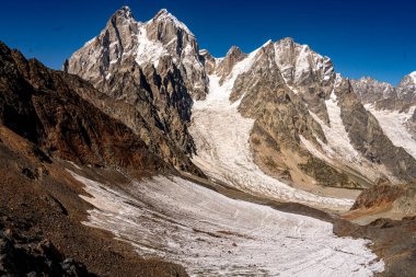 Gürcistan 'ın Kafkasya bölgesindeki Ushba Dağları ve Buzul Dağları engebeli kayalıkları ve açık mavi gökyüzü altındaki karla kaplı görkemli dağlık arazi. Yüksek kalite fotoğraf