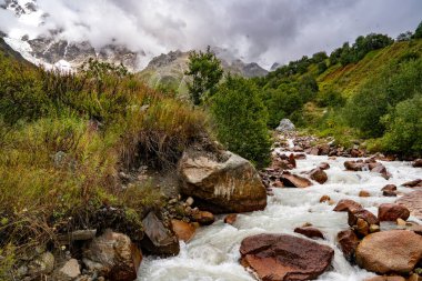 Ushguli Gürcistan yakınlarındaki Kafkasya Dağları 'ndaki Shkhara Buzulu: Engebeli tepeleri, kayaları ve sisli gökyüzü olan görkemli Alp manzarası. Yüksek kalite fotoğraf