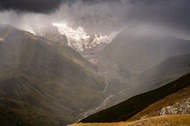 Georgia 'nın Kafkasya Dağları' ndaki Shkhara Vadisi 'nin üzerindeki Fırtına Bulutları ve Puslar Buzul ve Engebeli Yabanın Çarpıcı Manzarası. Yüksek kalite fotoğraf
