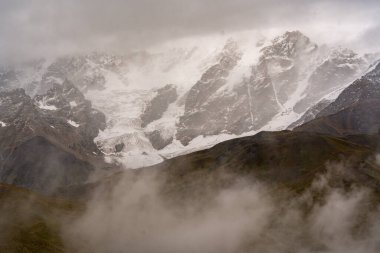 Georgia 'nın Kafkasya Dağları' ndaki Shkhara Vadisi 'nin üzerindeki Fırtına Bulutları ve Puslar Buzul ve Engebeli Yabanın Çarpıcı Manzarası. Yüksek kalite fotoğraf