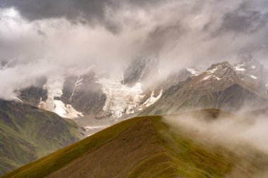 Georgia 'nın Kafkasya Dağları' ndaki Shkhara Vadisi 'nin üzerindeki Fırtına Bulutları ve Puslar Buzul ve Engebeli Yabanın Çarpıcı Manzarası. Yüksek kalite fotoğraf
