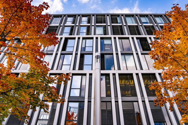 Modern Office Building With Autumn Garden Pathway: Contemporary Glass Architecture Surrounded By Colorful Trees And Soft Evening Lights In Urban Setting. High quality photo