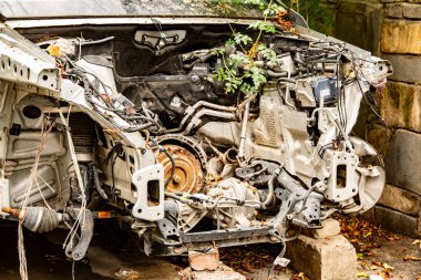 Ön Parçası Olmayan Hasarlı Araba Kanadı Taş Duvarın yanına park edilmiş: Kayıp Motorlu Paslı Araç ve Şehir Çürüme Sahnesindeki Aşırı Gelişmiş Fabrikalar. Yüksek kalite fotoğraf