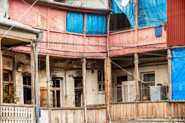 Tiflis Georgia 'daki eski ahşap balkon: Yıkanmış boya, kırsal pencereler ve akşam vakti çamaşır asma ile yıpranmış mimari. Yüksek kalite fotoğraf