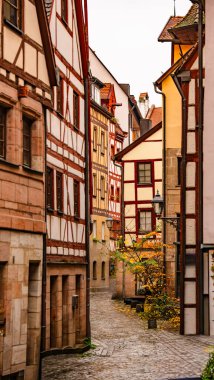 Nuremberg 'deki Büyüleyici Eski Sokak: Tarihi yarım keresteli evler ve sıcak bir ortaçağ atmosferi yaratan sonbahar yapraklı Dar Çakıl Taşı Sokağı. Yüksek kalite fotoğraf
