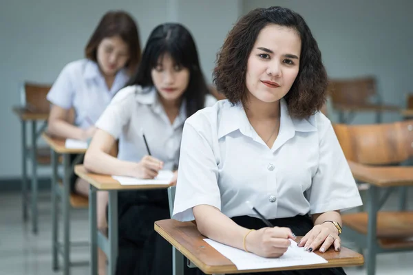 在课堂上写作和学习的快乐的亚洲女大学生的画像 在课堂学习的有选择的重点青少年大学生 — 图库照片