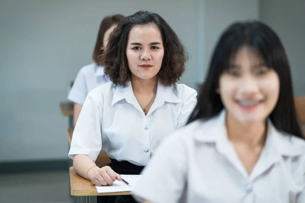 在课堂上写作和学习的快乐的亚洲女大学生的画像 在课堂学习的有选择的重点青少年大学生 — 图库照片